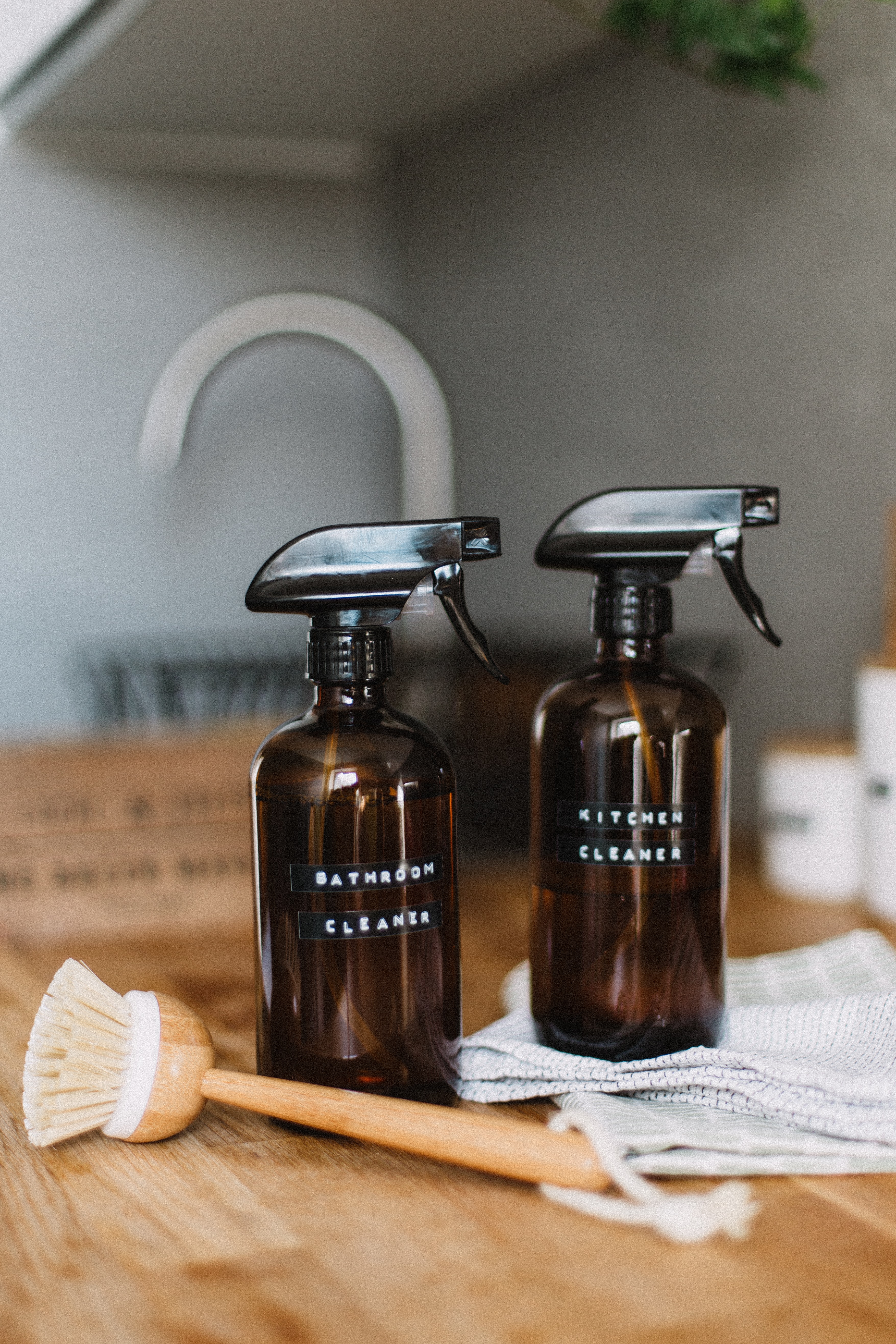 bottles of homemade bathroom and kitchen cleaning products on a wooden worksurface